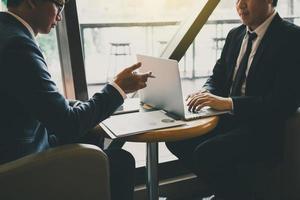 Two businessmen are talking about the results of operations in the company financial statements on the computer screen. photo