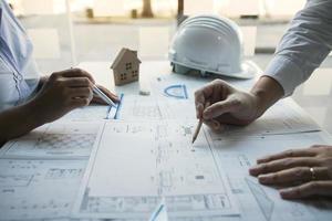 Two architect working at construction site and compass drawing pointing on blueprint with partnership. photo