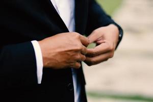 The groom tightens his cufflinks before the wedding photo