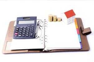 Home paper and coins stack with calculator and eyeglasses on business memo for Mortgage loans concept photo