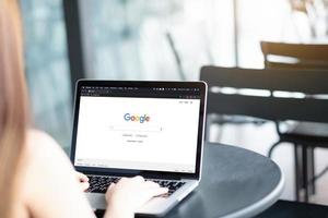 una mujer está escribiendo en el motor de búsqueda de google desde una computadora portátil. Google es el motor de búsqueda de Internet más grande del mundo. foto
