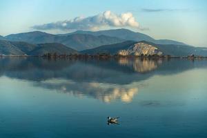 Mountains reflecting in the water of a blue lake and a swimming mallard photo