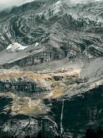 Terrible lifeless rocks, a glacier in the Alps, clouds and fog spread over the peaks of the mountains photo