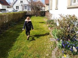 Little girl running in the flowering garden, spring time photo