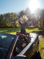 una hermosa chica posando en un descapotable, un auto retro y una belleza bajo el brillante sol de otoño. foto