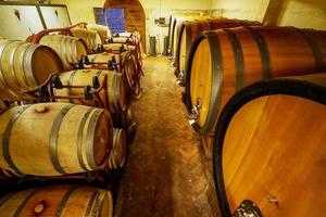 Oak barrels of wine in the basement of an Italian winemaker. Old wine production technology.