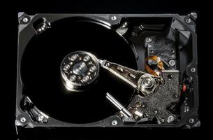 Disassembled and opened hard disk drive, inside view with reflections, isolated on black photo