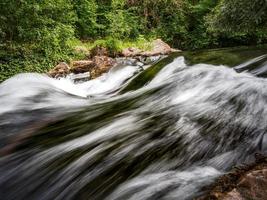 Small but fast rapid with a waterfall on a mountain river, forest, Alsace. photo