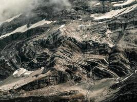 terribles rocas sin vida, un glaciar en los Alpes, nubes y niebla esparcidas sobre los picos de las montañas foto