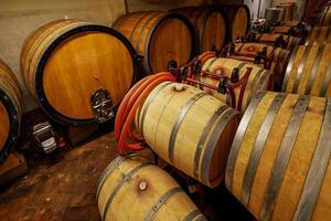 Barriles de vino de roble en el sótano de un enólogo italiano. antigua tecnología de producción de vino. foto