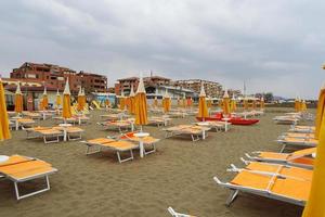 Lined up sunbeds on a deserted beach on a cloudy day. Tuscany photo