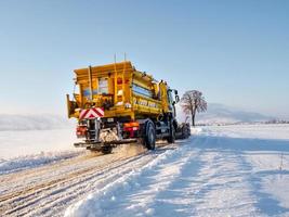 A snowblower clears the road in the snowy fields of Alsace. Movement, sun, purity. photo