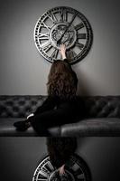 chica y tiempo. hermosa joven posando contra el fondo de un reloj de pared foto