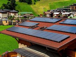 Green hills of an alpine resort in Austria in summer. Small village, hotels and chalets, all in colors. Beautiful terraces and solar panels on the roofs. The proximity of civilization and pure nature.