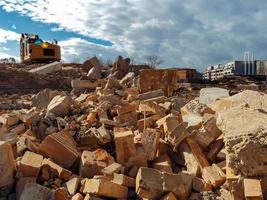 An excavator breaks down an old building. Dust, bricks and broken walls. photo