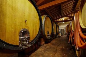 Barriles de vino de roble en el sótano de un enólogo italiano. antigua tecnología de producción de vino. foto