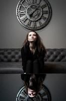 chica y tiempo. hermosa joven posando contra el fondo de un reloj de pared foto