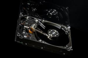 Disassembled and opened hard disk drive, inside view with reflections, isolated on black photo