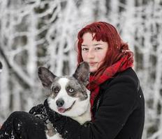 retrato de una niña en la nieve con su mascota - corgi. foto