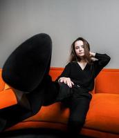 Beautiful young girl posing on a beautiful bright orange sofa photo