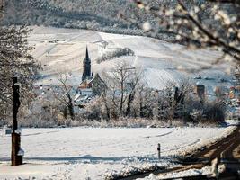 An old Alsatian town under the snow. The bell tower of the cathedral and the roofs of medieval houses. photo