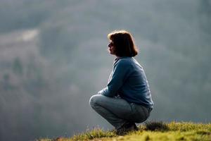 Woman silhouette. Sitting on the hill. Relaxation and tranquility. photo