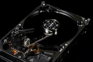 Disassembled and opened hard disk drive, inside view with reflections, isolated on black photo