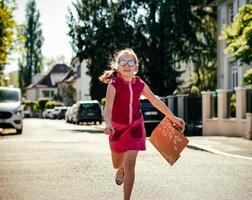 Emotional photos of a schoolgirl girl who runs along the street in the bright sun.