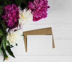 invitation card, craft envelope and pink peony flowers photo