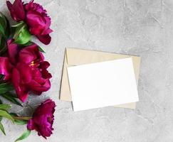 tarjeta de invitación, sobre artesanal y flores de peonía rosa foto