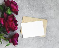 tarjeta de invitación, sobre artesanal y flores de peonía rosa foto