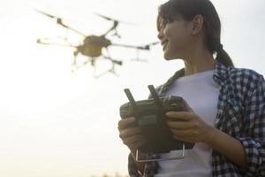 joven agricultor inteligente que controla la fumigación de fertilizantes y pesticidas con drones sobre tierras de cultivo, innovaciones de alta tecnología y agricultura inteligente foto