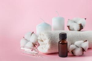 Natural cosmetic products for spa and aromatherapy. Relaxation concept. Candles, flowers and a towel on a pink background.