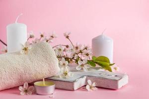 Natural cosmetic products for spa and aromatherapy. Relaxation concept. Candles, flowers and a towel on a pink background. photo