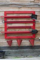 Set of useful tools in case of fire. Red conical fire buckets, shovels,  hanging on a wooden facade near Baikal Lake, Siberia, Russia. photo