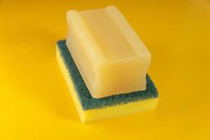 Kitchen sponge and soap bar on the yellow background photo