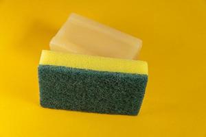 Kitchen sponge and soap bar on the yellow background photo