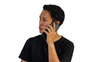 joven asiático con camisa negra hablando por teléfono con fondo blanco. foto