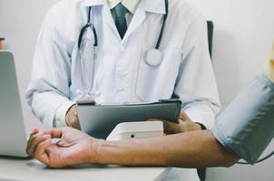 doctor measures the blood pressure of an elderly male patient. photo