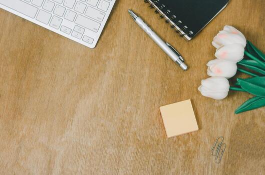 Top view flat lay notebook and flower and pen with keyboard computer on wood table.Copy space photo
