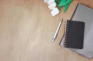 vista superior plana pone el cuaderno y la flor y la pluma en la mesa de madera. copie el espacio foto