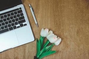 Top view flat lay computer laptop and flower on wood table.Copy space photo