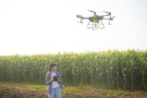 Young smart farmer controlling drone spraying fertilizer and pesticide over farmland,High technology innovations and smart farming photo