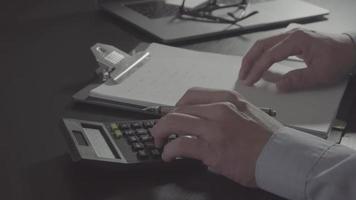 mano de hombre de negocios trabajando con finanzas sobre costos y calculadora y computadora portátil con teléfono móvil en el escritorio en la oficina moderna
