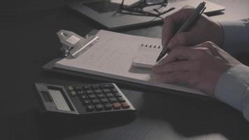 main d'homme d'affaires travaillant avec les finances sur le coût et la calculatrice et l'ordinateur portable avec téléphone portable sur le bureau blanc dans un bureau moderne video
