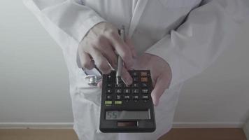 concepto de costos y tarifas de atención médica. La mano de un médico inteligente usó una calculadora para costos médicos en un hospital moderno video