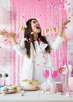 hermosa mujer celebrando la fiesta de cumpleaños lanzando confeti rosa foto