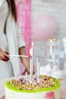 mujer con ropa de fiesta blanca preparando la mesa de cumpleaños, encendiendo las velas foto