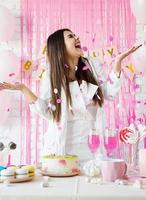 Beautiful woman celebrating birthday party throwing pink confetti photo