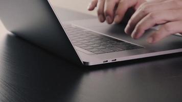 Businessman working with new modern laptop computer and eyeglasses on wooden desk in slow motion video